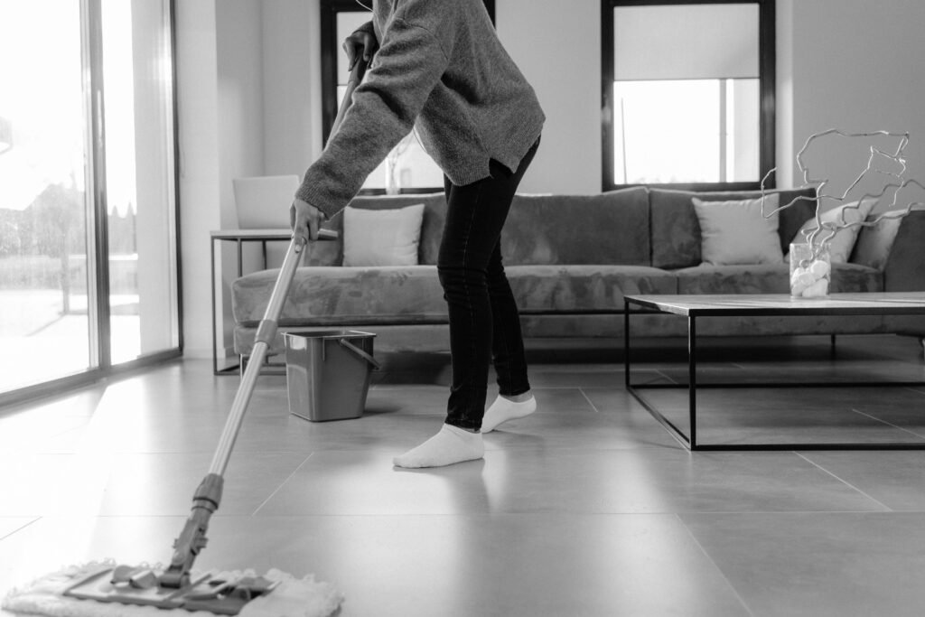 pexels-photo-6196567-6196567 A grayscale photo of a person mopping the floor in a modern living room.